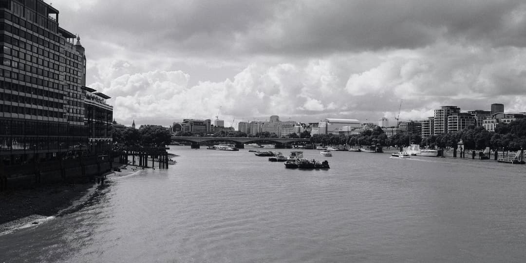 the river thames from the perspective of Blackfriars Bridge with some boats in the middle and looking onto another bridge in the background